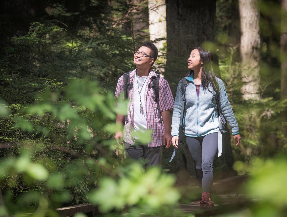 2 smiling people hiking in the woods